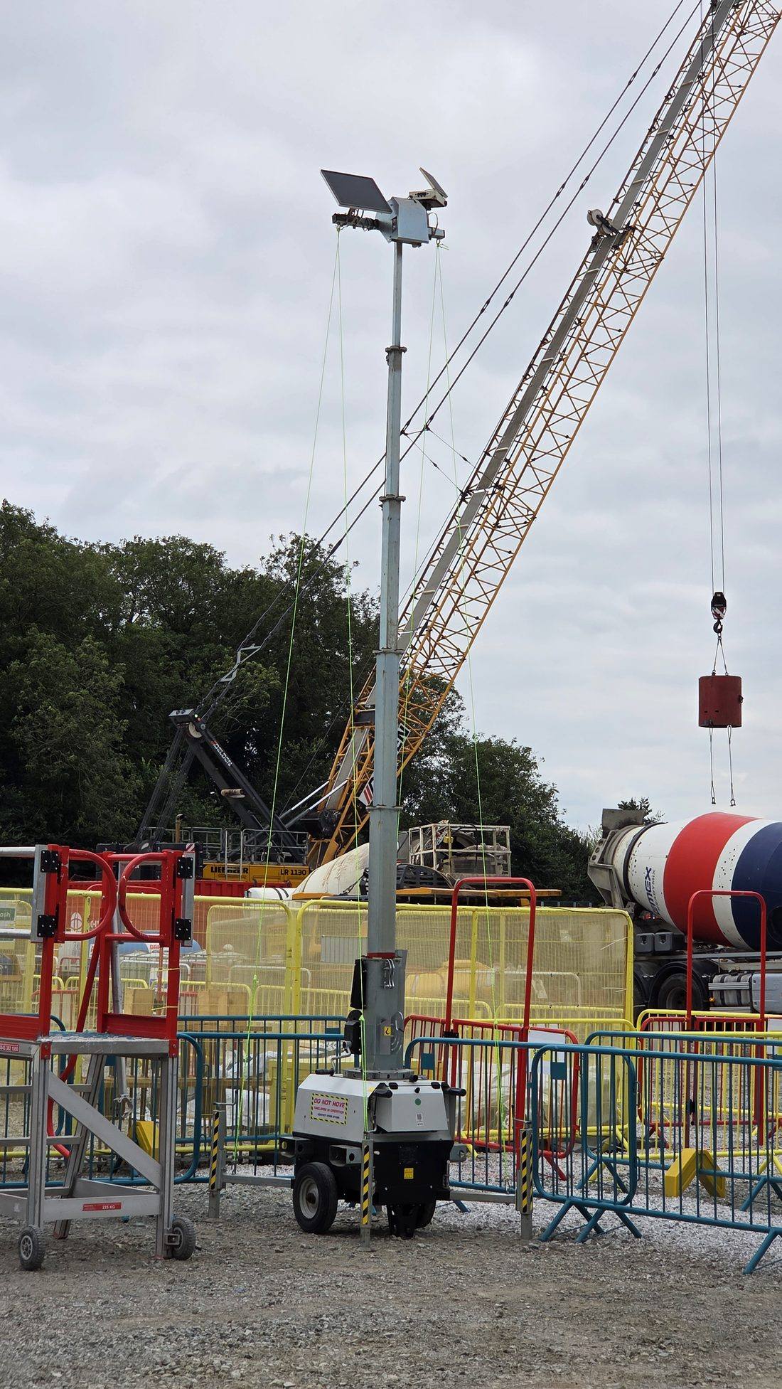 Tower mast up beside a crawler crane on a live site