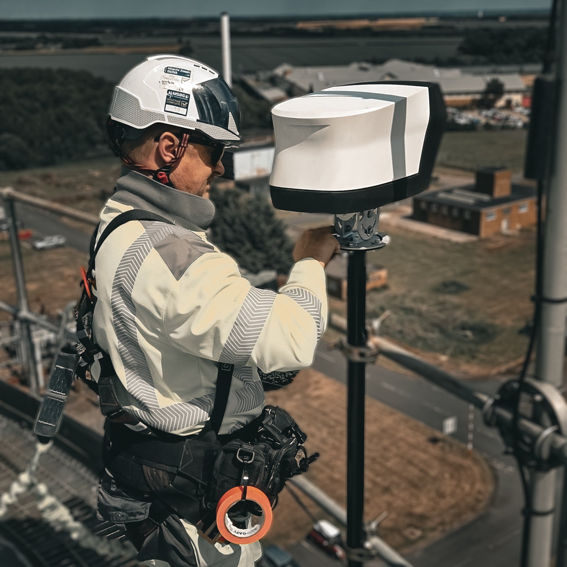 SkyGlide engineer fitting the white timelapse camera unit at height above an industrial site