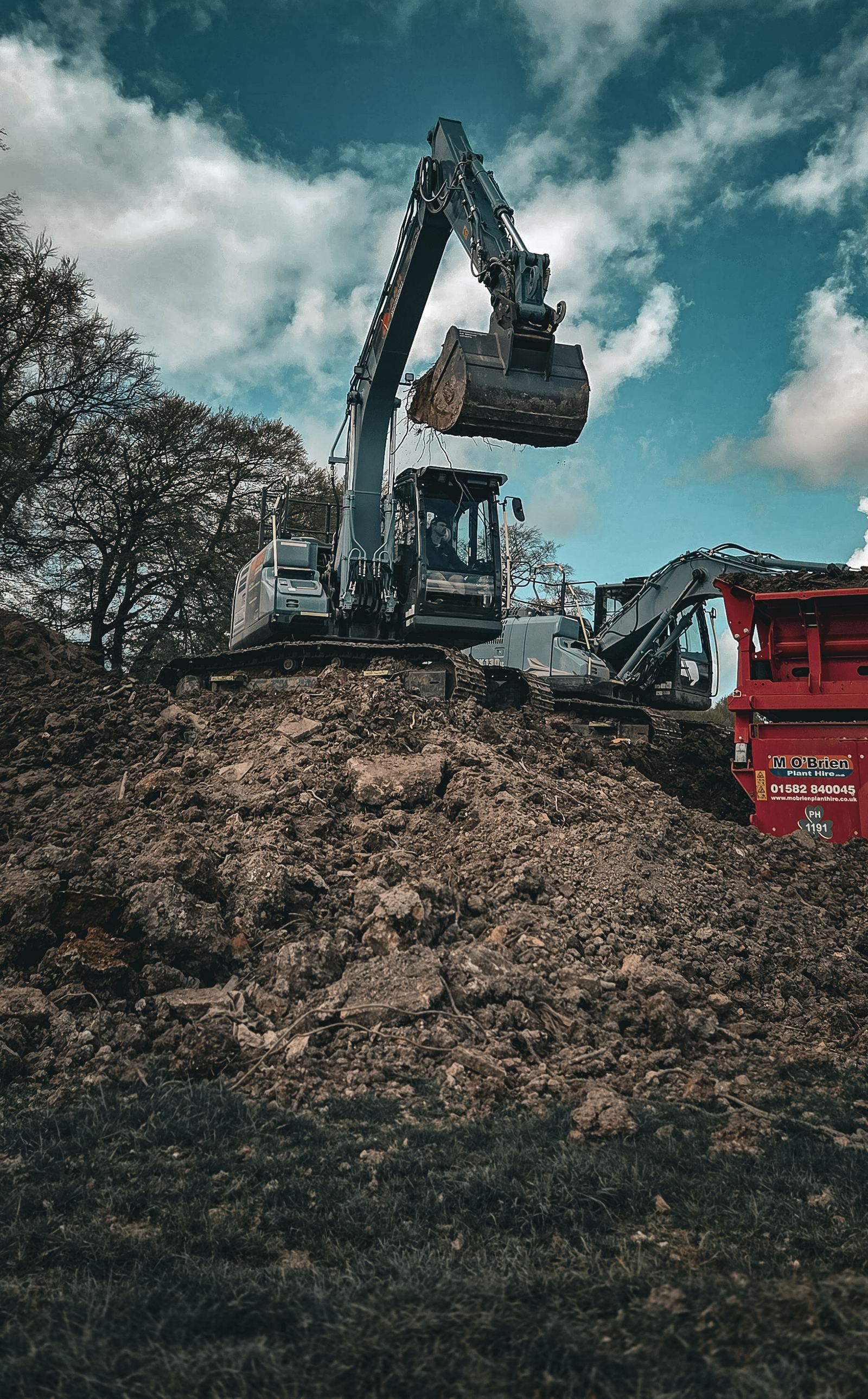 Excavator loading a screener on a muck shift under a dramatic sky