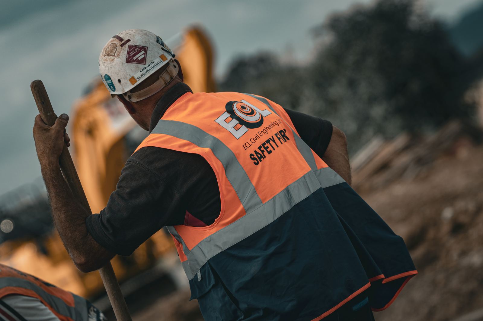 Civil engineering operative working ahead of an excavator