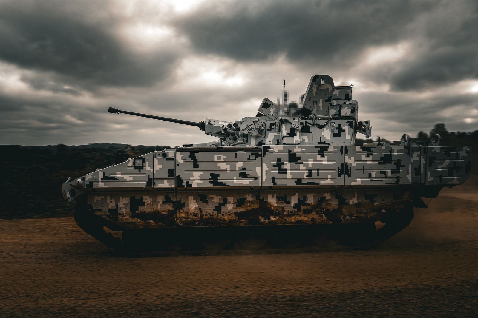 Tracked fighting vehicle in digital camouflage panning past under storm clouds